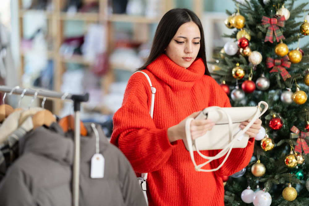 Young woman choosing handbag in store