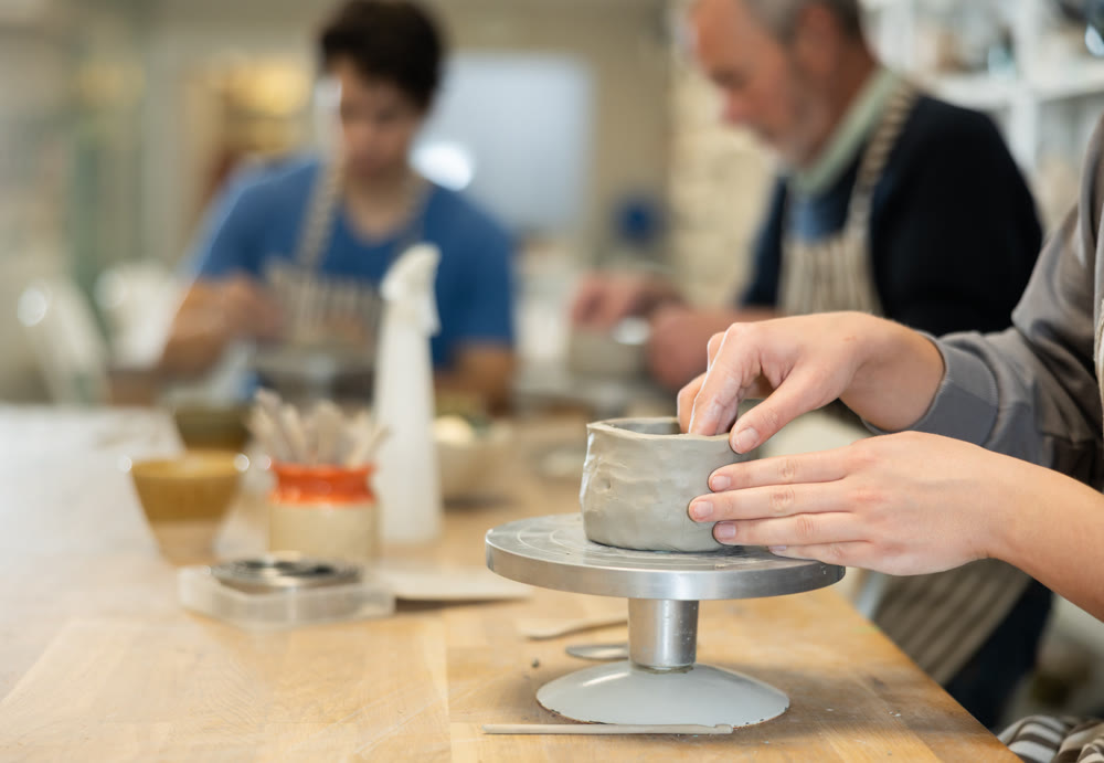 Closeup of female hands sculpting at a table in pottery studio