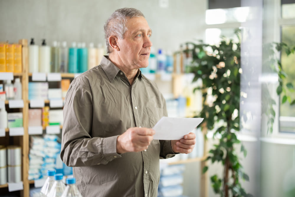Senior man with prescription looking for products in pharmacy