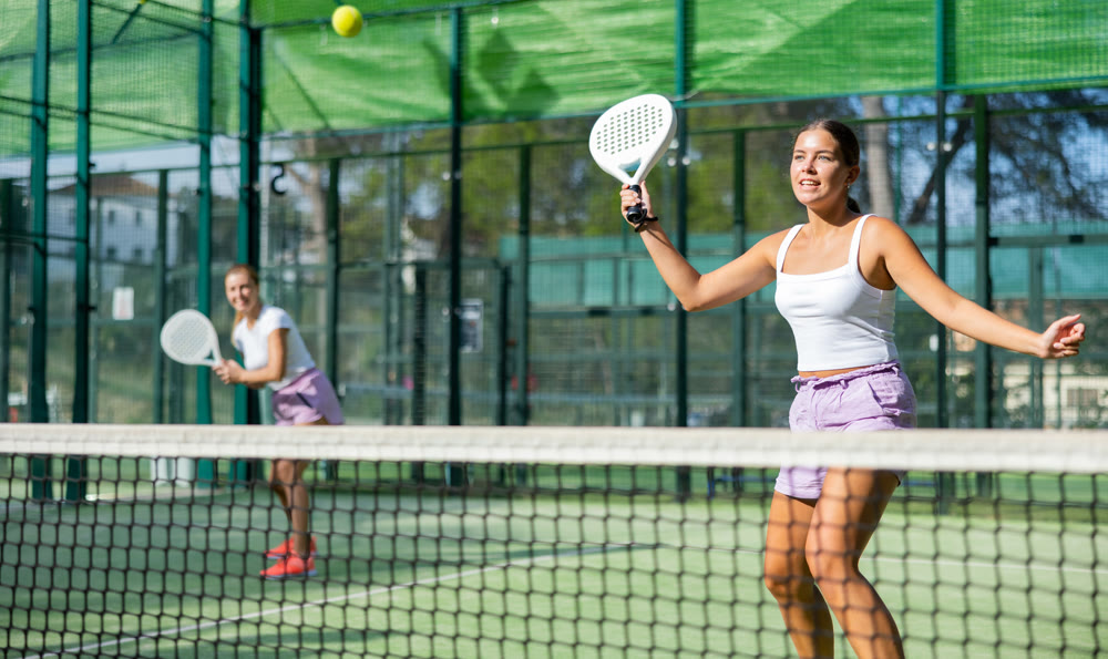 Padel game - woman with partners plays on tennis court