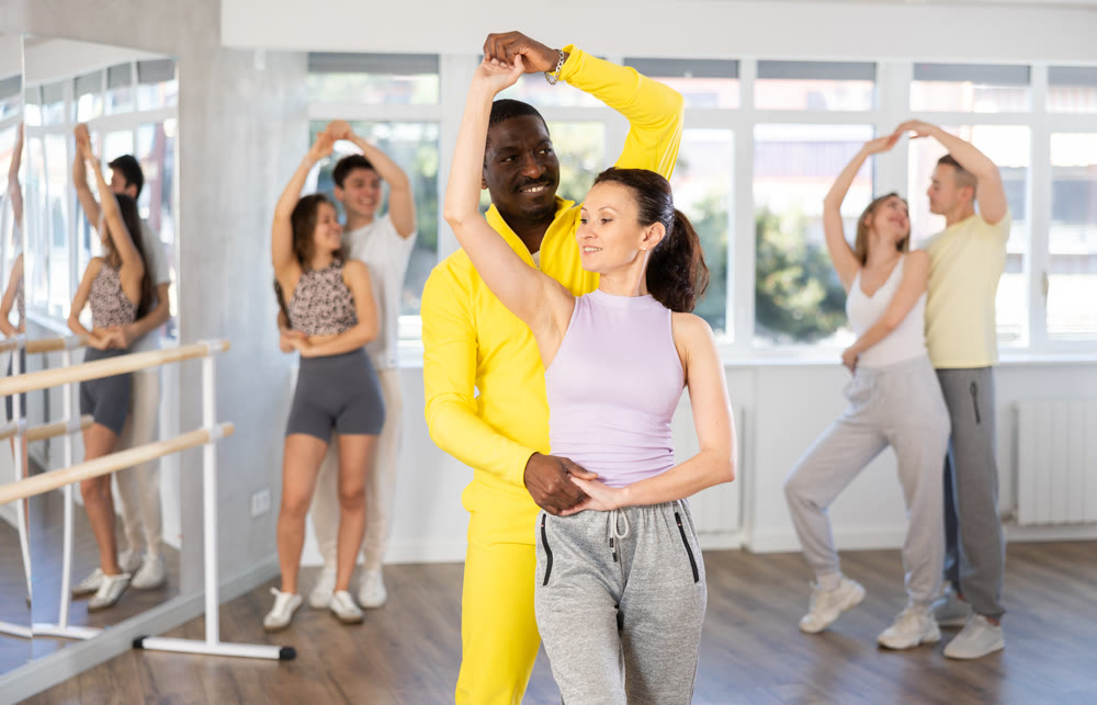 Middle-aged man and woman practicing waltz dance in pair in training hall
