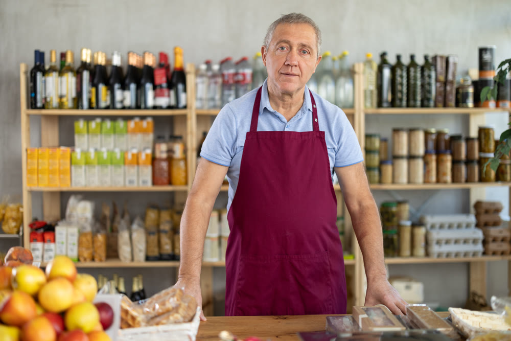 Elderly man seller at counter in grocery store
