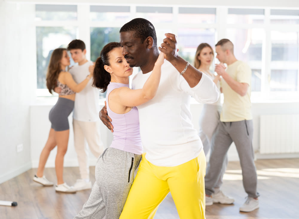 Woman with African man dancing waltz in couple during lesson at studio