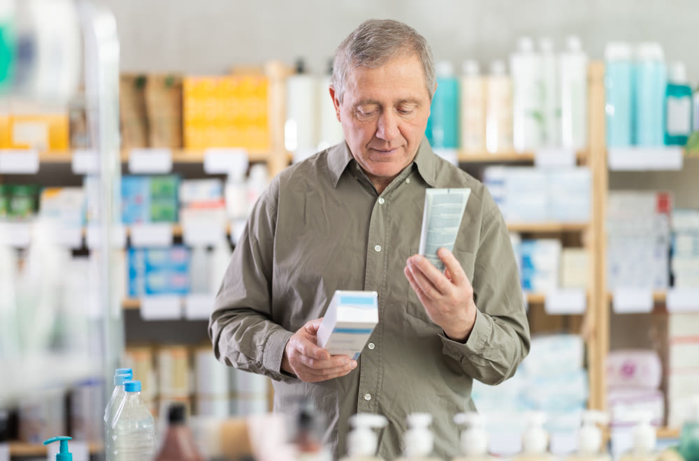 Elderly man choosing a cream at the pharmacy