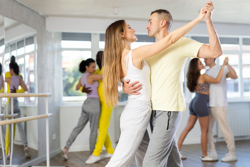 Man and young woman dancing waltz in couple during lesson at studio