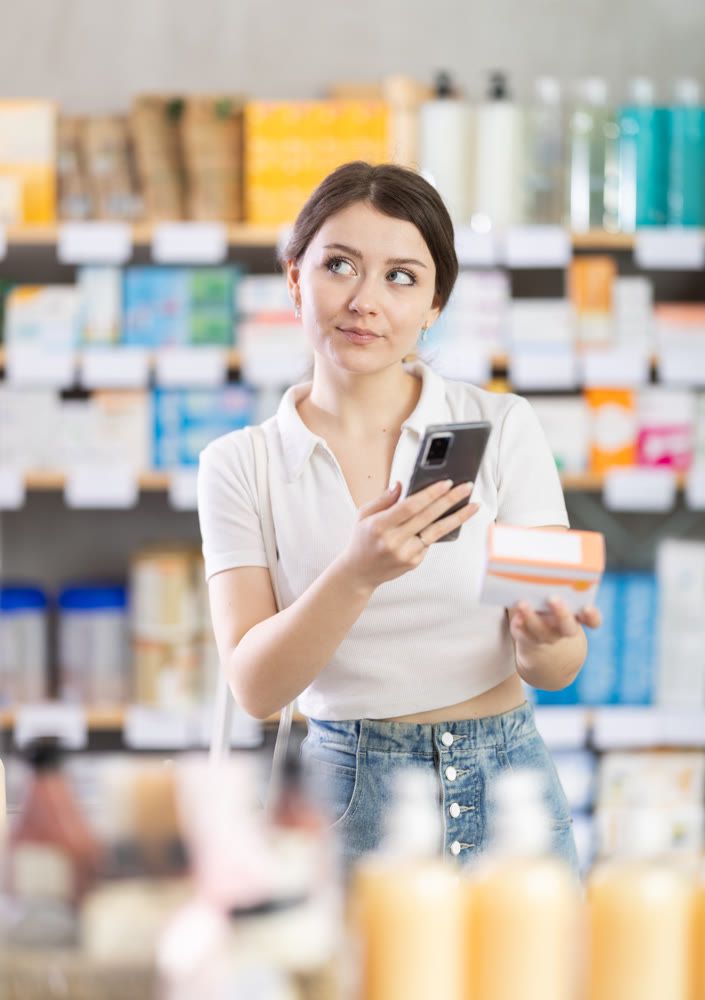 Female customer scanning QR code on pills with phone in drugstore