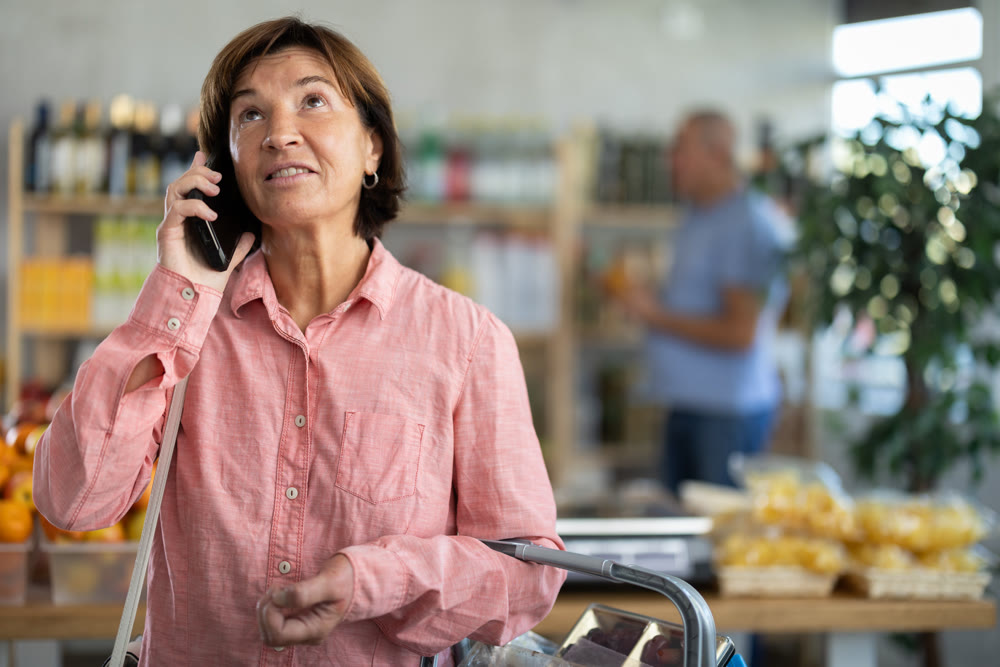 Elderly woman choosing groceries while talking on phone