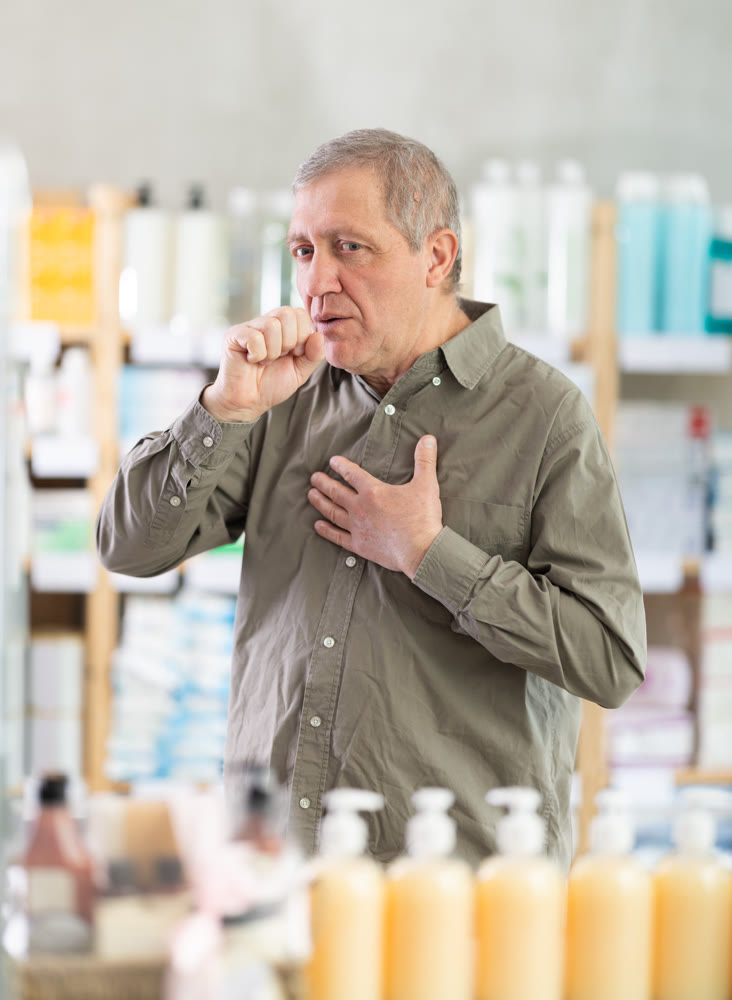 Senior man visits pharmacy and suffers from cough