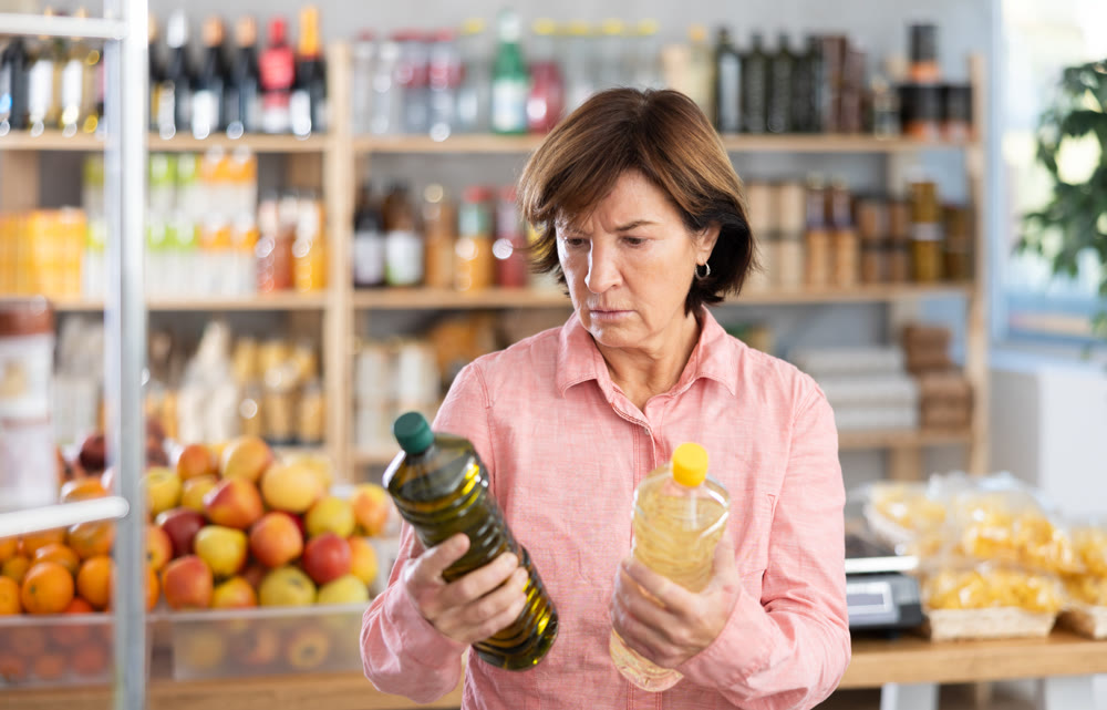 Mature woman choosing vegetable oil in grocery store