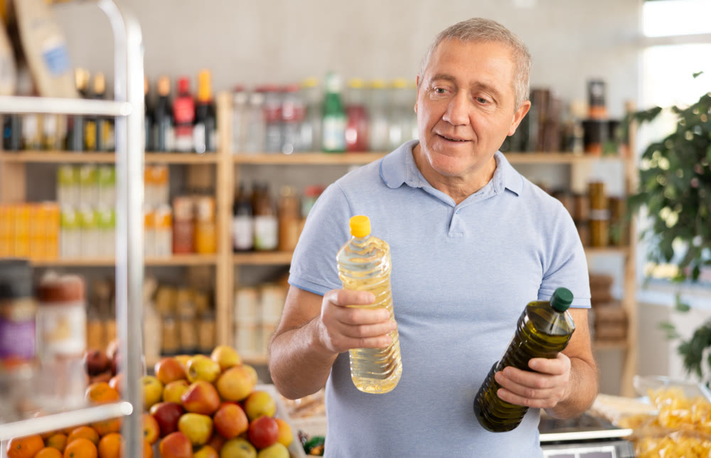Mature man choosing vegetable oil in grocery store