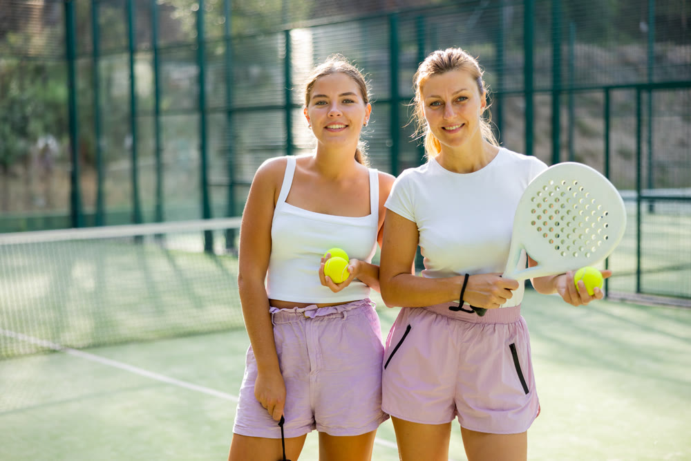 Portrait of positive women on padel tennis court