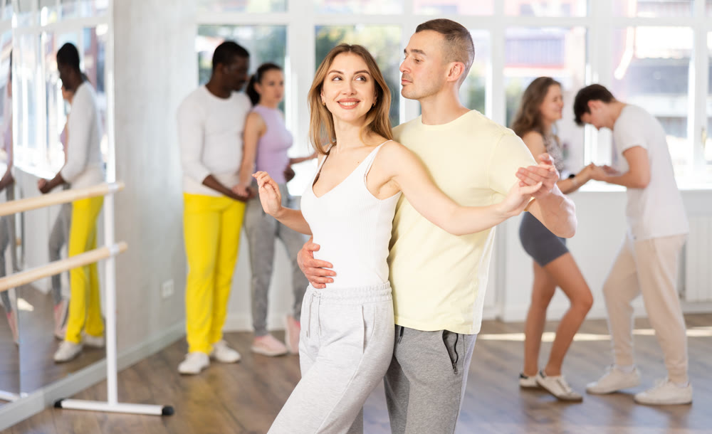 Smiling man and woman enjoying impassioned merengue at dance class