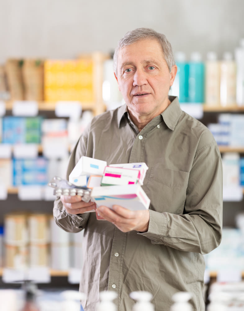 Elderly man comparing medications in pharmacy aisle