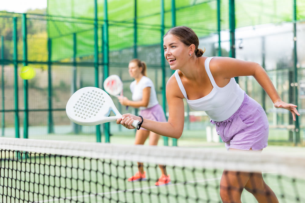 Young woman padel tennis player trains on the outdoor court