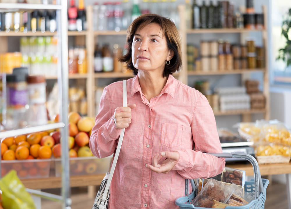 Portrait of female shopper choosing variety of products in grocery hypermarket
