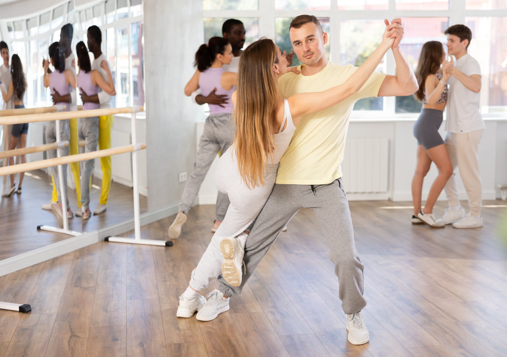 Young man and woman practicing salsa dance in pair in training hall
