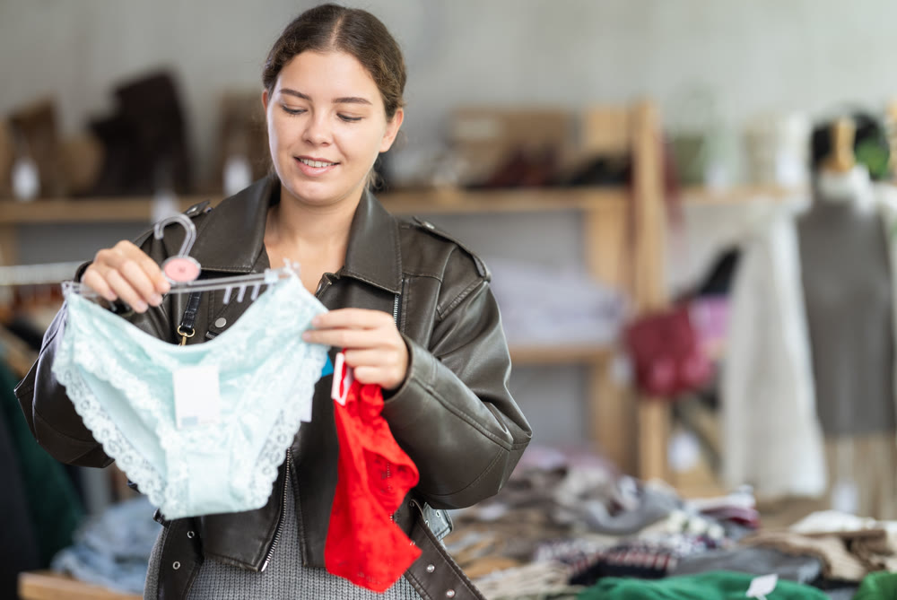 Cheerful young girl buyer choosing comfort panties in clothing store