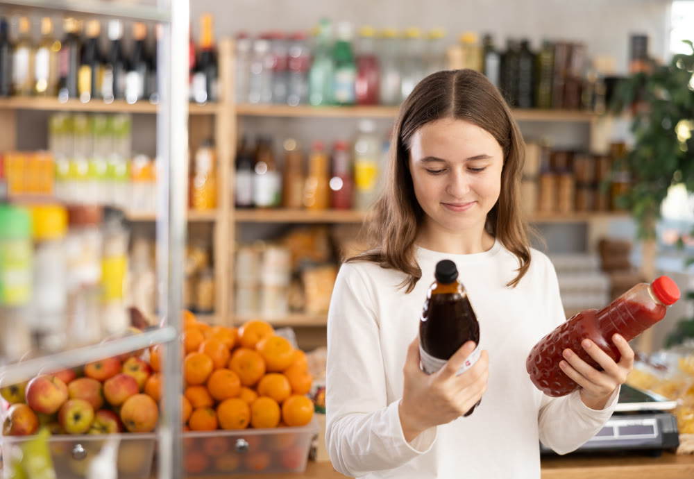Teenage girl chooses pomegranate and tomato juices