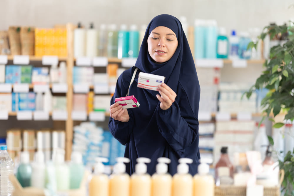 Young Muslim woman customer choosing paracetamol in drugstore