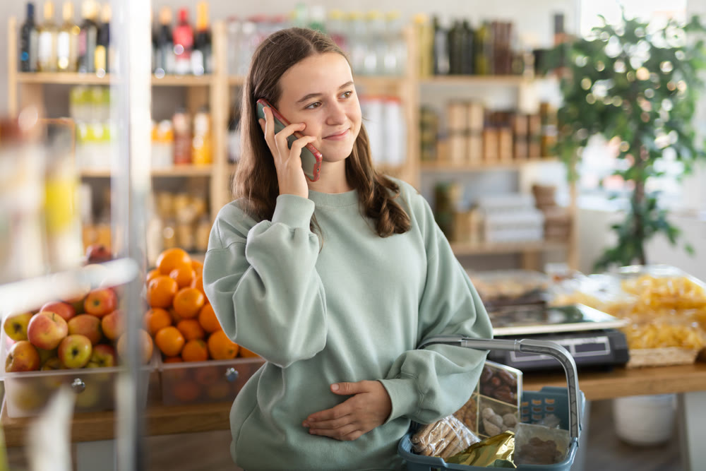 Teenage girl choosing groceries while talking on phone