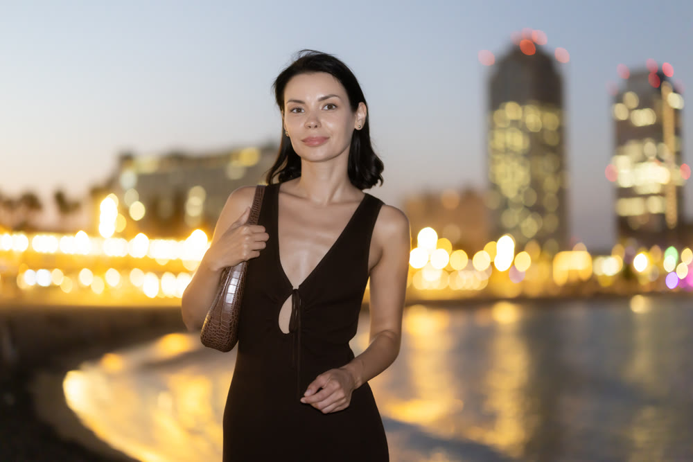 Young woman standing at seaside against background of twin towers