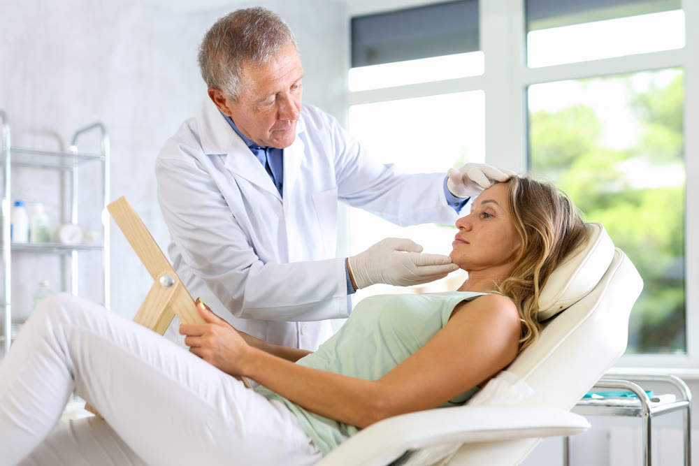 Elderly man doctor examining adult woman patient
