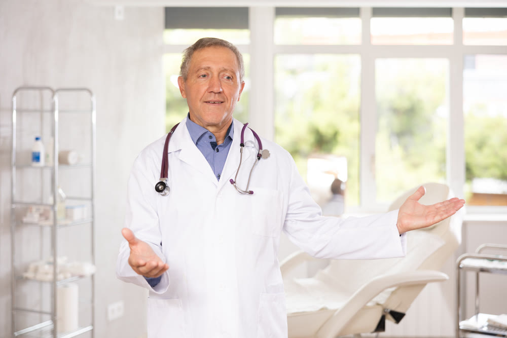 Elderly male doctor posing in medical office