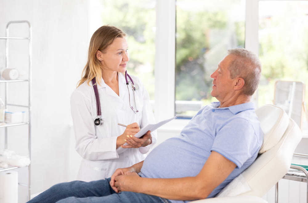 Female doctor with document folder talking to senior male patient