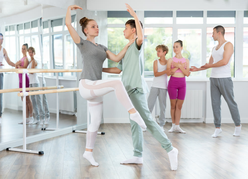 Teenage girl and boy practicing ballet positions in pair in dance studio