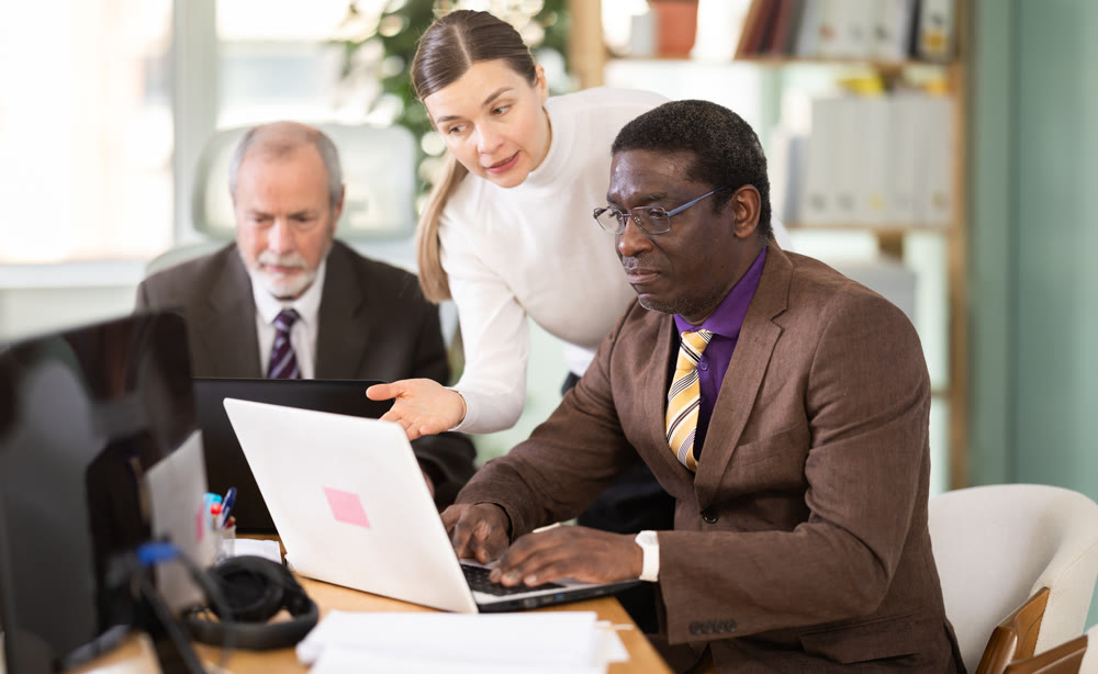 Woman help to african man work on laptop