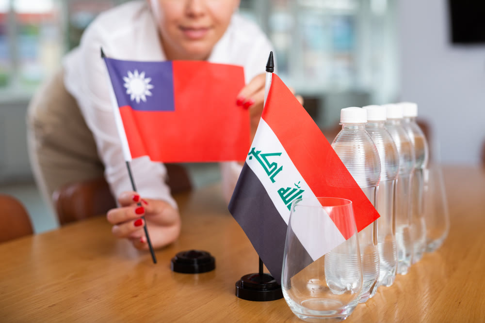 Preparing for business presentation - secretary places flags of Iraq and Taiwan on negotiating table