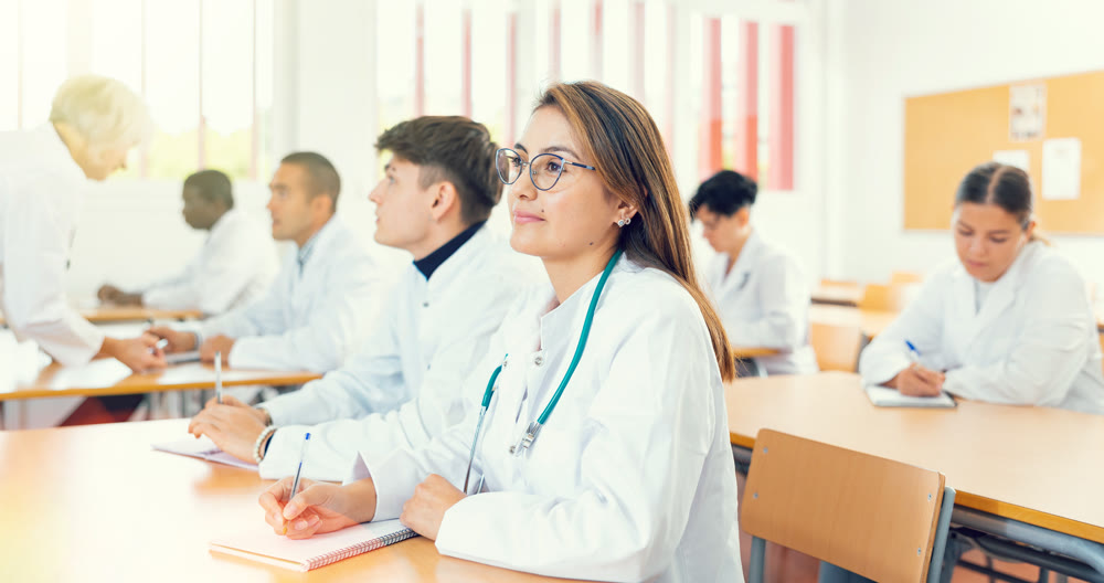 Doctors different age sitting at desk in classroom working during lesson at education class