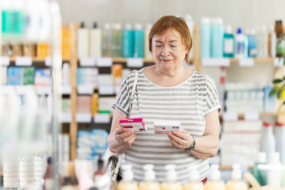 Mature woman in summer clothes buys paracetamol medicine at pharmacy