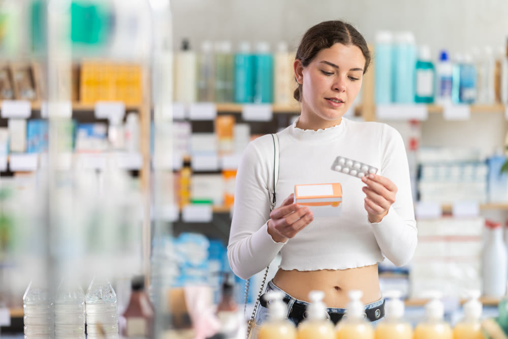 woman in summer clothes chooses a package of pallets in a pharmacy