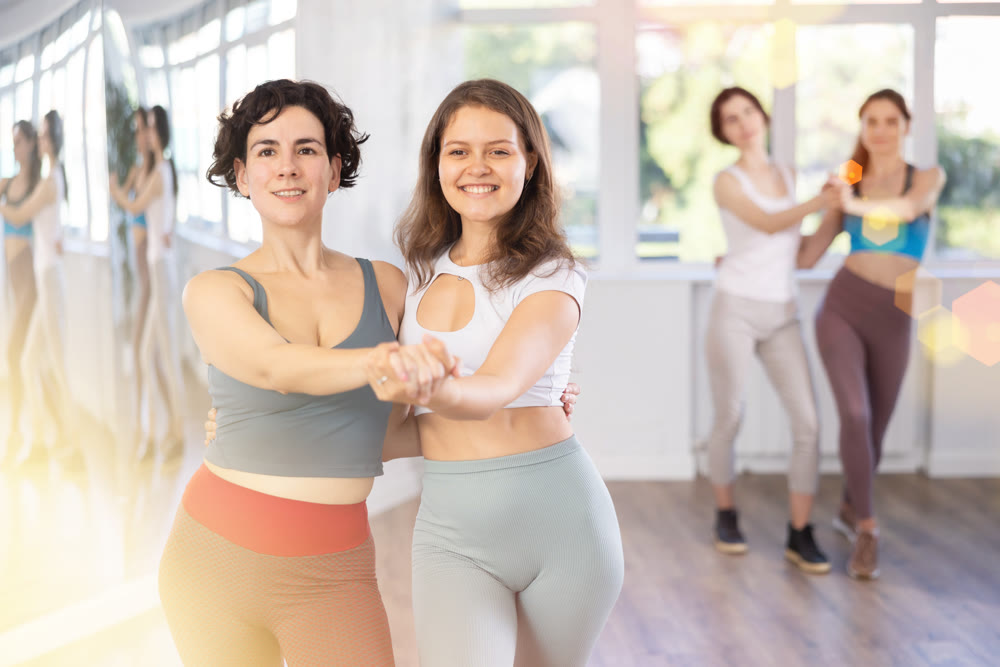 Cheerful girls learn to dance together modern and classical dances in dance studio