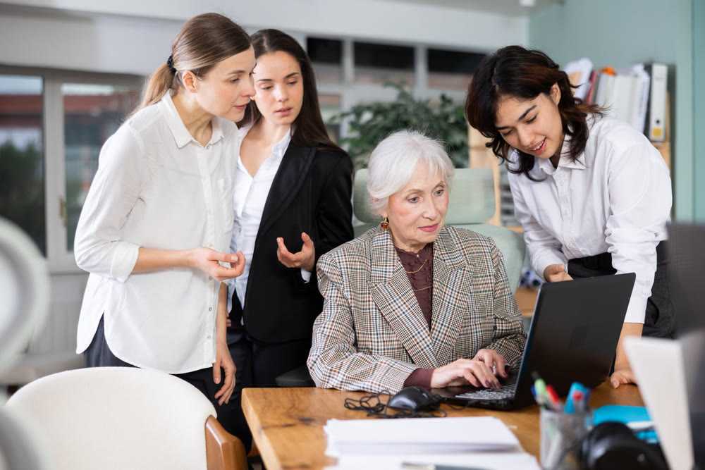Group of women discussing work around laptop in office