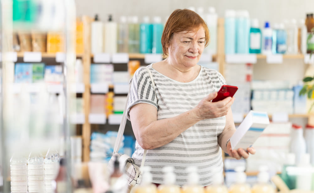 Senior woman in pharmacy scans QR code on cream