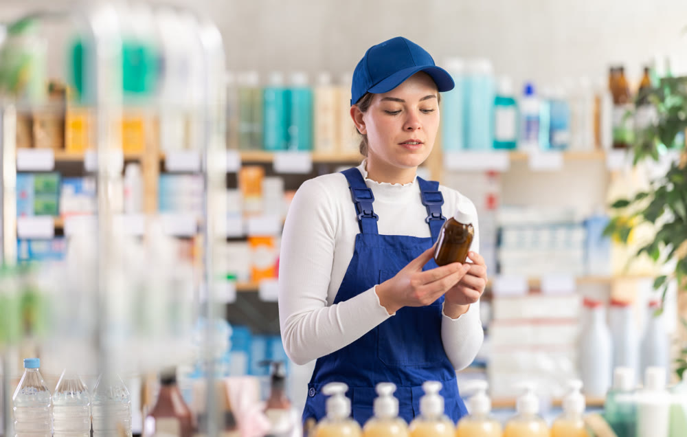 In sales area of pharmacy, builder woman examines packaging of expectorant syrup