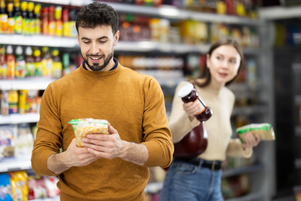Man customer in supermarket search and select product beans