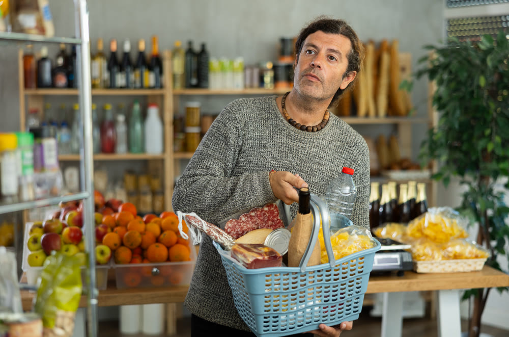 Man with purchses basket shopping for fresh groceries in store