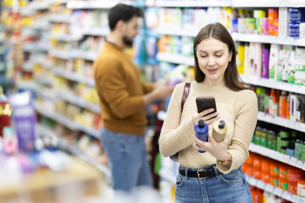 Woman get acquainted with good, scan QR code, take reading label using phone camera in shop