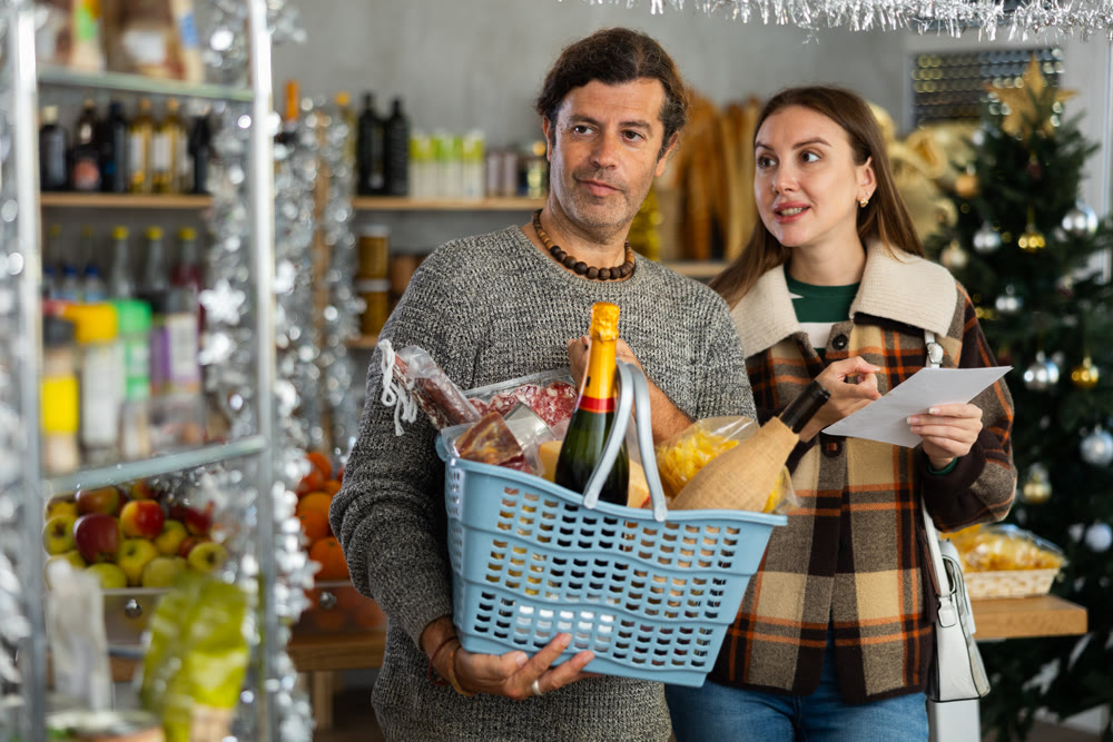 Happy couple shopping for Christmas snacks from list in festive store