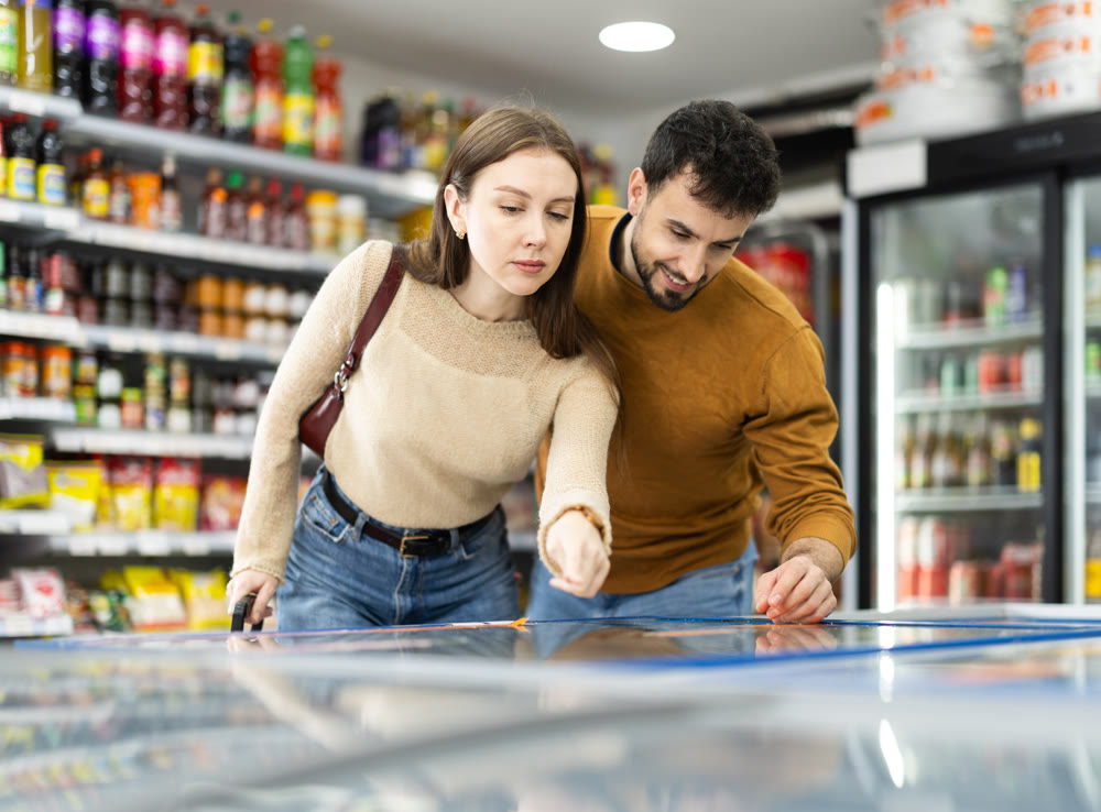Young couple choosing frozen food in grocery store