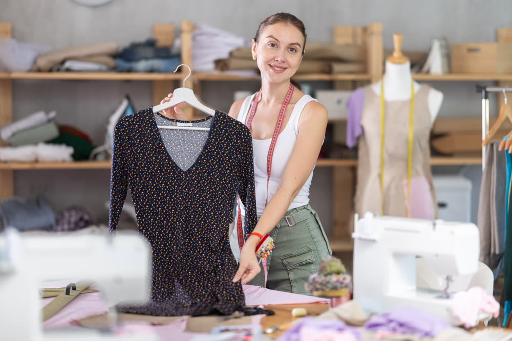 dressmaker presents a ready-made dress in a workshop