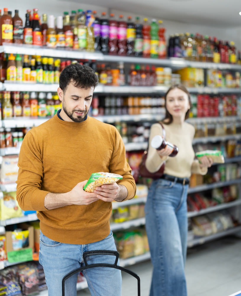 Couple of shoppers are choosing nuts and other food products in food store