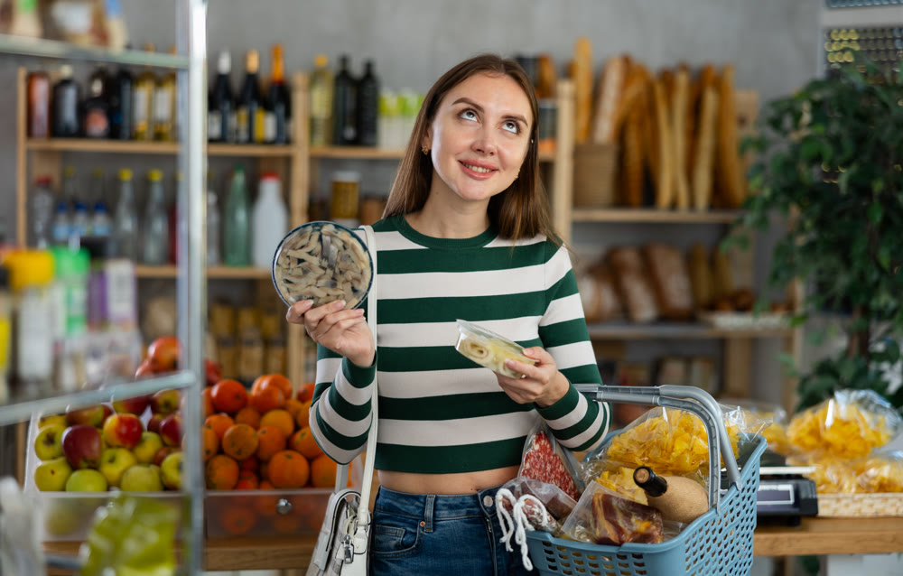 Preparing for Christmas celebration - girl chooses salted herring in produce section of supermarket
