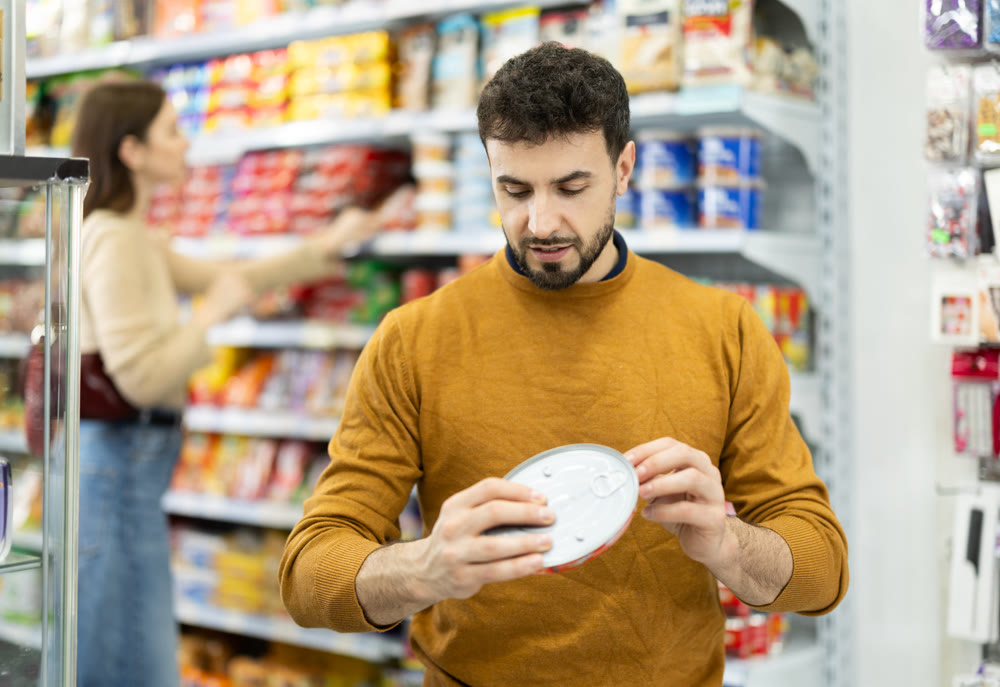 Man in supermarket search and select product tin can