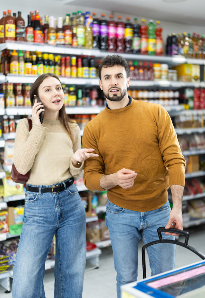 Young couple shopping for groceries woman talks on phone