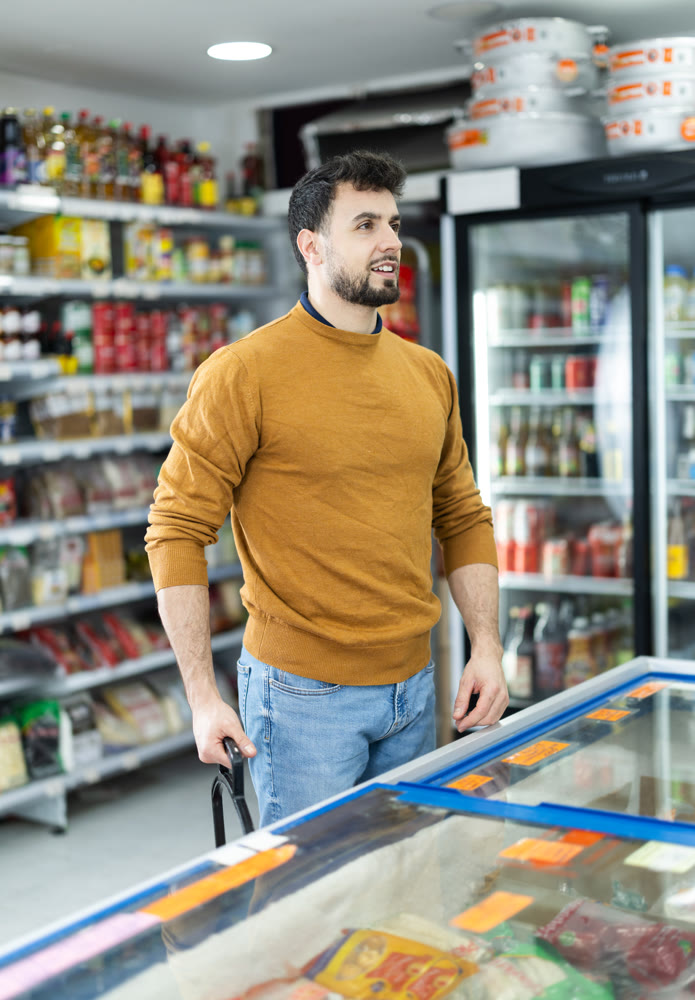 Young man choosing frozen food in grocery store