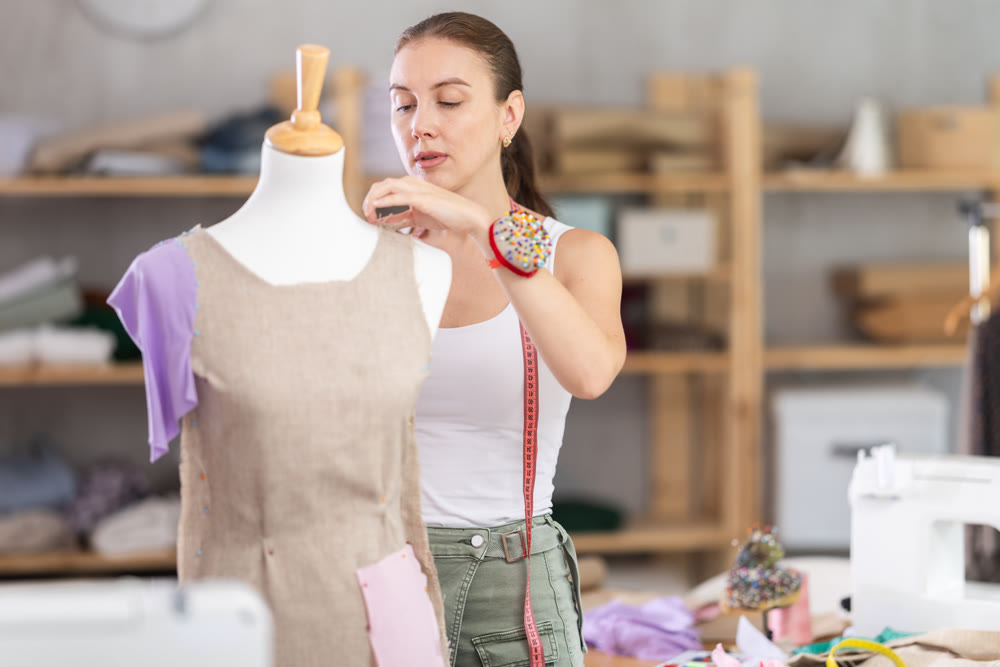 Girl designer works with mannequin and dress billet